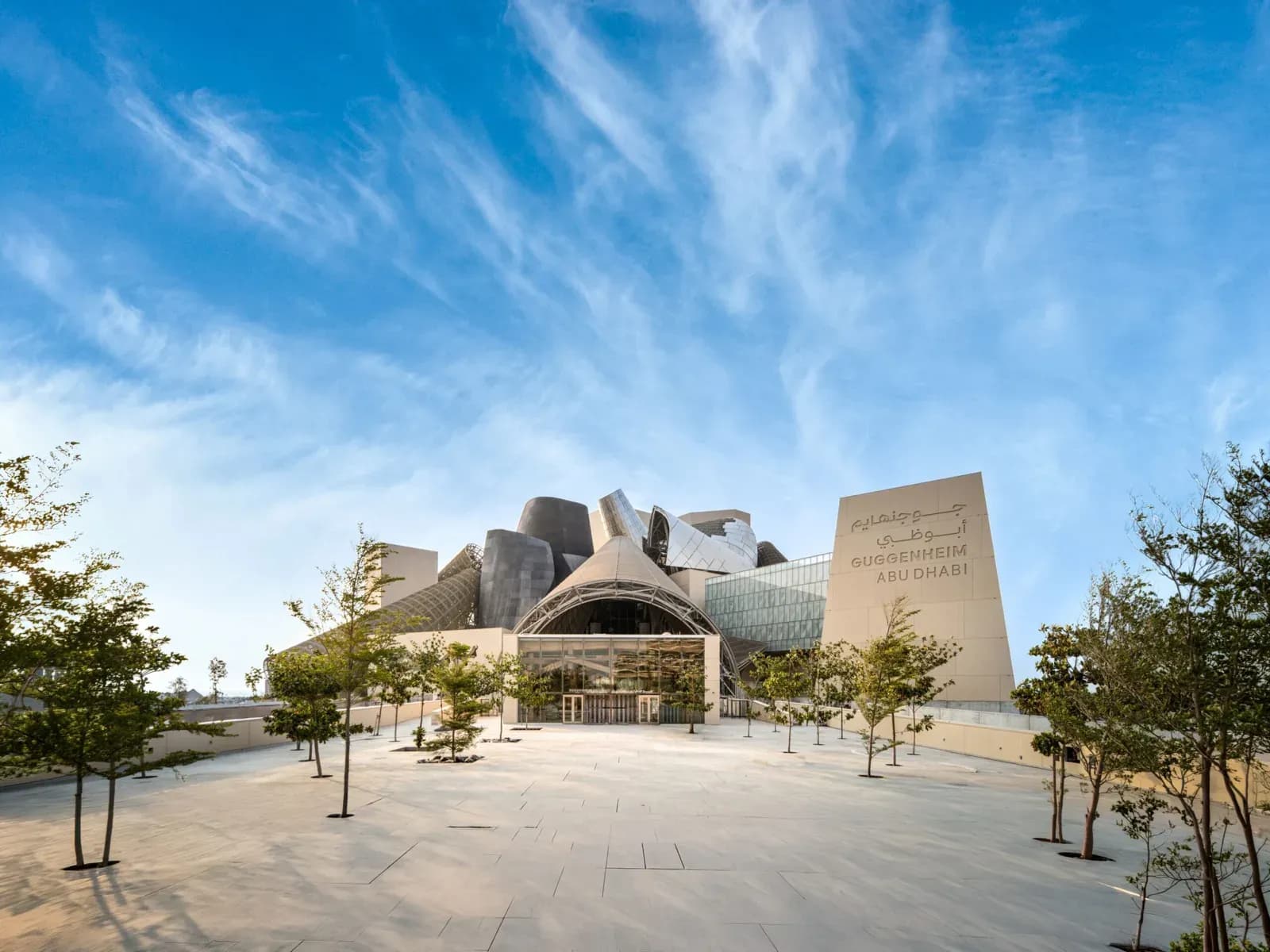 The Guggenheim Abu Dhabi building seen from its forecourt, with clustered metal-clad cones behind the entrance canopy