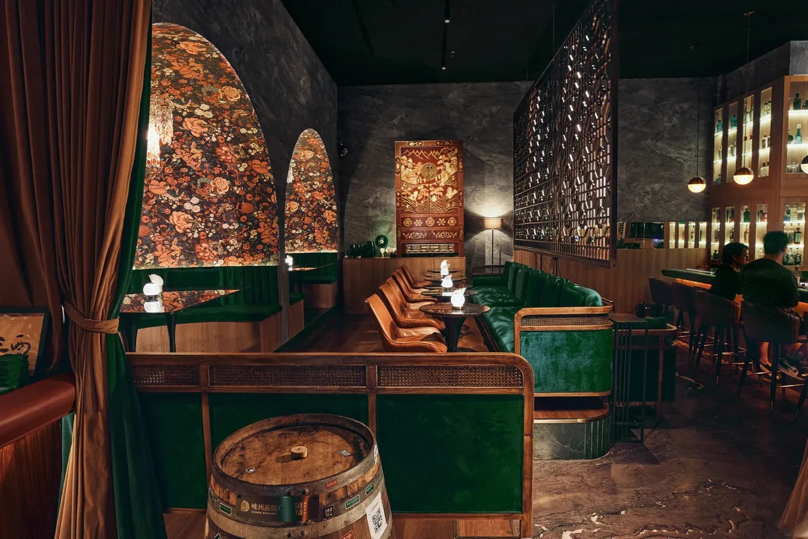 The interior of Hope and Sesame in Guangzhou, with green velvet banquettes, floral arched panels and the bar counter along the right
