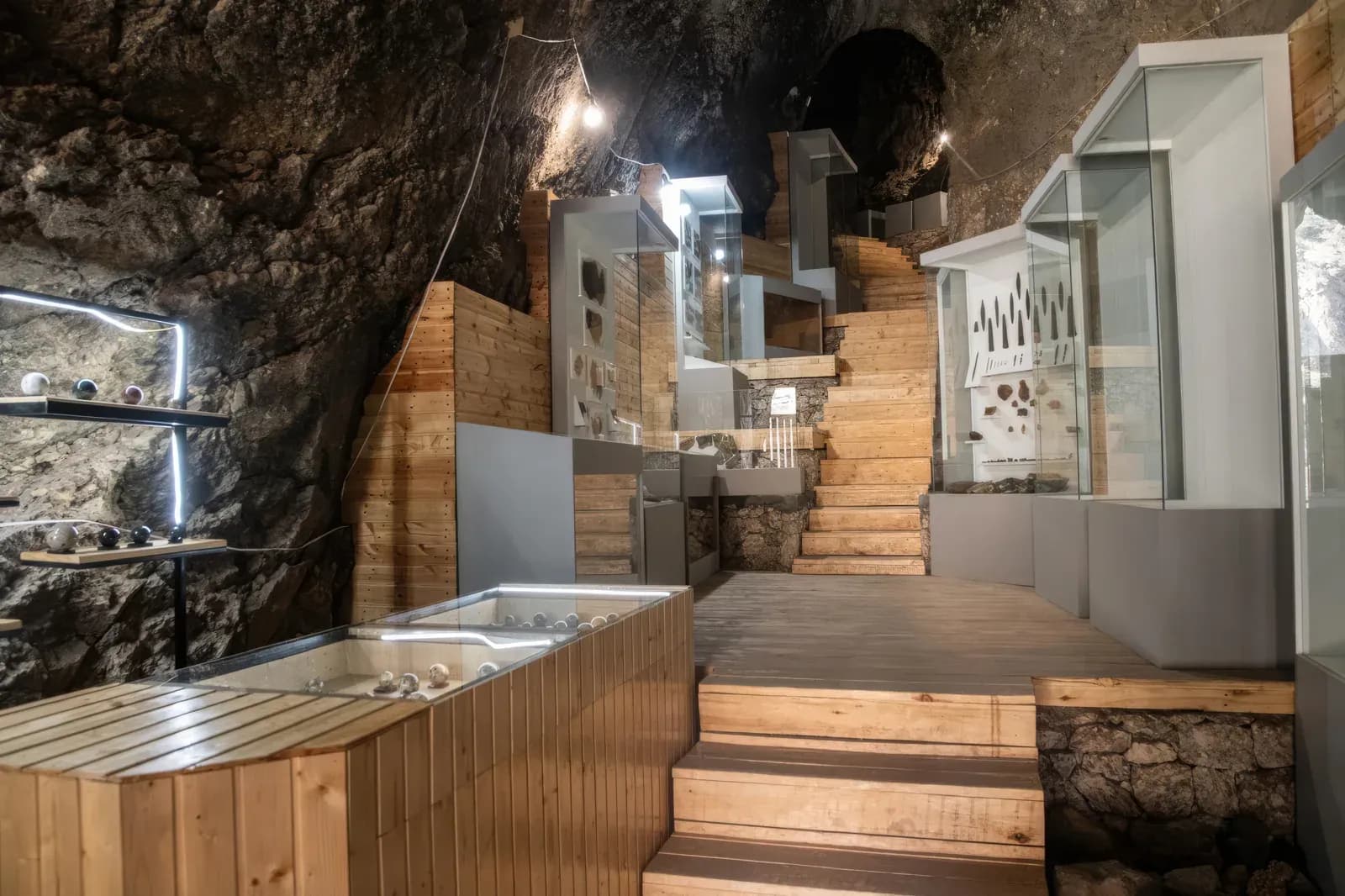 Wooden walkways and lit glass display cases installed inside the rough rock of the Areni-1 cave in southern Armenia