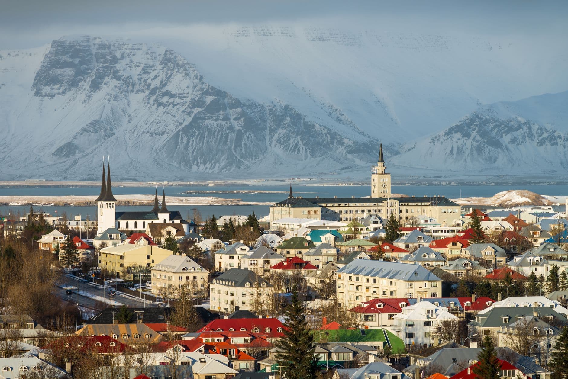 A breathtaking aerial view of Reykjavik cityscape in winter with snow-capped mountains in the background.